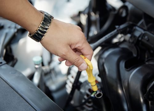 Car mechanic checking oil level in car engine